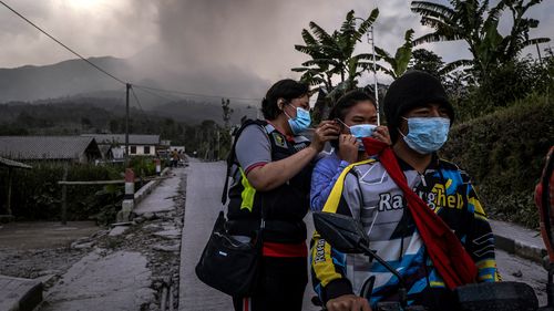 Des agents distribuent des masques aux villageois dans une zone couverte de cendres après l'éruption du mont Merapi crachant des matériaux volcaniques dans le village de Stabelan le 11 mars 2023 à Boyolali, dans le centre de Java, en Indonésie. 