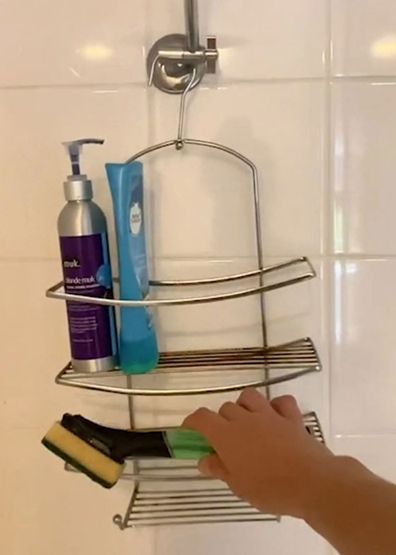 Dishwand filled with detergent on a shower caddy for easy cleaning