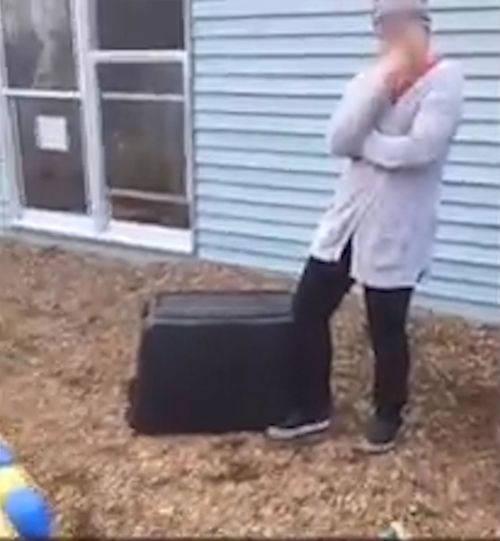 The staff member appears to be laughing as the toddler is stuck under the container. (KCCI)