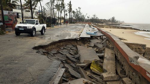A car drives by a destroyed section of the road after Tropical Cyclone Idai, in Beira, Mozambique.