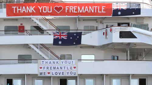 The MV Artania is seen with "Thank You Fremantle" banners and Australian flags positioned on the side of the vessel while berthed at the Fremantle Passenger Terminal