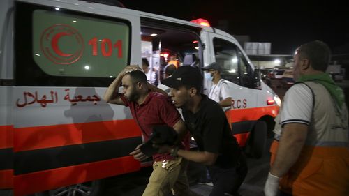 Palestinian medics help a man wounded in Israeli strikes to in Shifa Hospital in Gaza City, Friday, Oct. 13, 2023. (AP Photo/Ali Mahmoud)