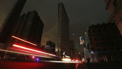 Les voitures sont floues lorsqu'elles passent devant un Flatiron Building sombre dans une partie de Manhattan toujours en panne d'électricité après l'ouragan Sandy le 30 octobre 2012 à New York. 