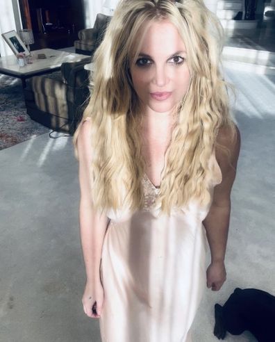 Britney Spears standing in beige dress looking directly at camera