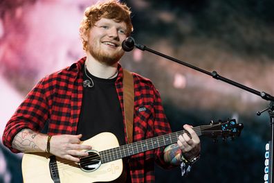 Ed Sheeran playing guitar with mic at concert 