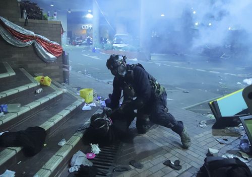 A policeman in riot gear detains a protester outside of Hong Kong Polytechnic University as police storm the campus in Hong Kong