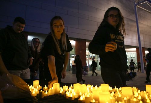 Mourners are handed out electric candles during a candlelight vigil at the University of Nevada Las Vegas. (AAP)