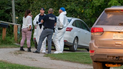 Police officers stand at a crime scene in Weldon, Saskatchewan