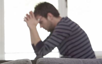 Man sitting at table with head in hands upset