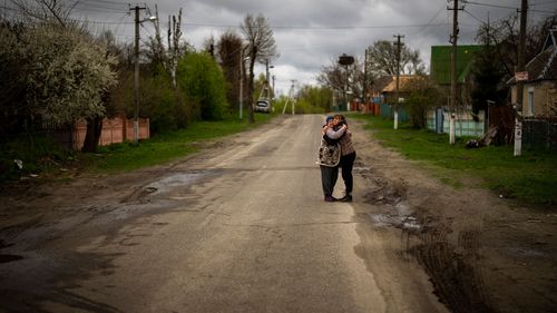 Tetiana Boikiv, 52, right, meets and hugs her neighbour, Svitlana Pryimachenko, 48, during a funeral service for her husband, Mykola "Kolia" Moroz, 47, in the Ukrainian village of Ozera, near Bucha.