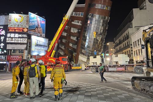 Rescue workers stand near the site of a leaning building in the aftermath of an earthquake in Hualien, Taiwan, on Wednesday, April 3, 2024
