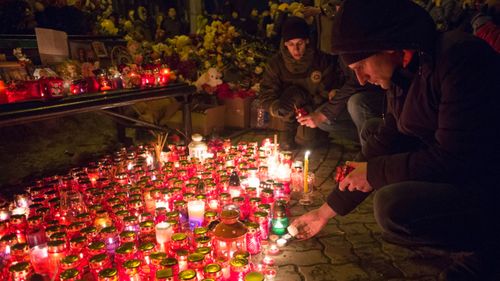 People light candles by a floral tribute for the victims of a fire in a multi-story shopping center in the Siberian city of Kemerovo. (AP).