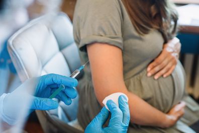 Pregnant woman getting vaccine at home. COVID-19 vaccination concept.