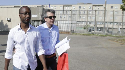Rudy Guede, left, is greeted by an unidentified person as he leaves the penitentiary for a temporary release of thirty-six hours, in Viterbo, Italy, on June 25, 2016.