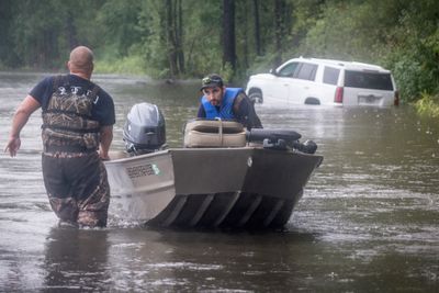 A Dillon County rescue crew boat works in a flooded area near a stuck car in Latta, South Carolina.