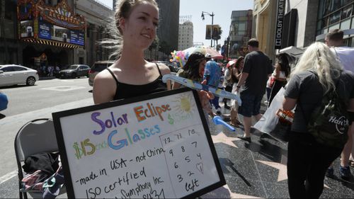 Sarah Mayes sells glasses to view the solar eclipse in Hollywood, California. (AAP)