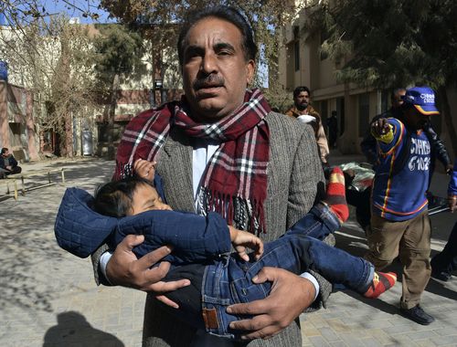A volunteer rescues a child while others removing a body following the suicide attack on a church in Quetta, Pakistan. (AAP)