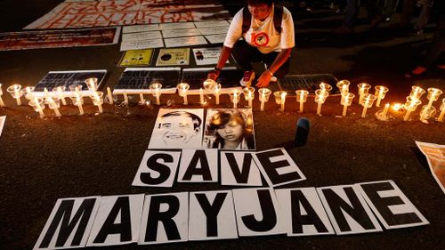 An Indonesian migrant worker activist lights candles during a candle light vigil supporting Filipino maid Mary Jane. (AAP)