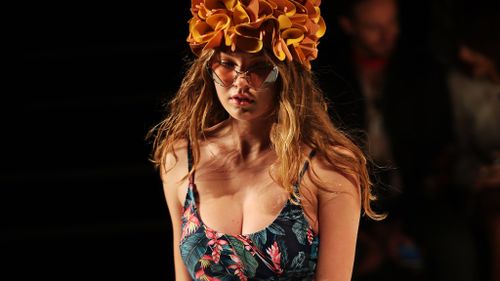 Neon floral swimsuits, accesorised by retro swimming caps, brought colour to the catwalk. (AAP)