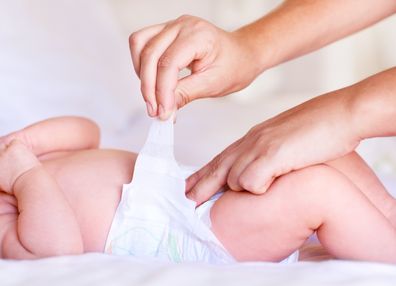 Cute baby boy relaxing while receiving a diaper change