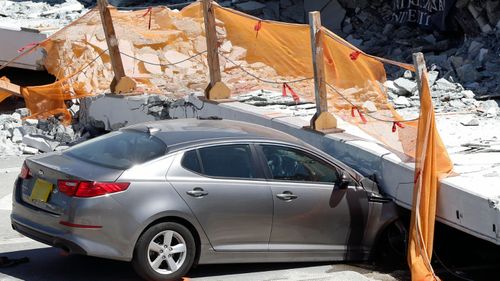A crushed car beneath a giant slab of concrete and steel. (AP).