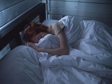 Woman asleep in bed stock photo.