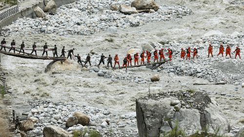 In this photo released by Xinhua News Agency, rescuers deliver supplies via a temporary bridge in the aftermath of an earthquake near Moxi Town of Luding County, southwest China's Sichuan Province, Sept. 8, 2022. Heavy rains are complicating earthquake recovery efforts in southwestern China, where the death toll from Monday's disaster has risen. (Shen Bohan/Xinhua via AP)