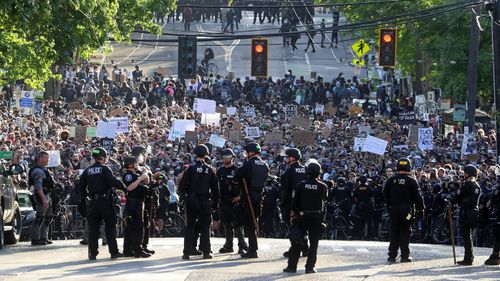 In this June 1, 2020 file photo a sea of peaceful protesters are kept back from the Seattle Police Department's East Precinct on Capitol Hill, by a two-block buffer of officers and gates,