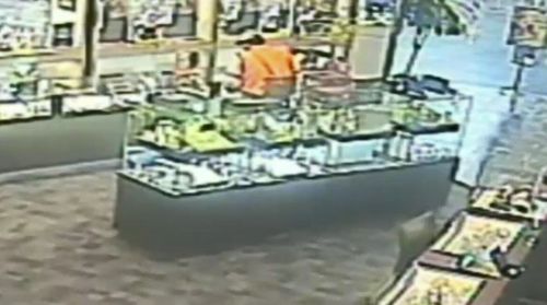 The footage shows a man, wearing a high-viz vest, jump the counter and smash the display cabinet before scooping jewellery into a bag.

