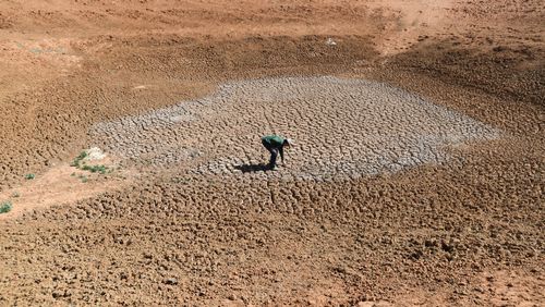 Broken Hill area farmer Lachlan Gall at the bottom of one of his dried-up dams.