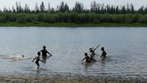 In this handout photo provided by Olga Burtseva, children play in the Krugloe lake outside Verkhoyansk, the Sakha Republic, about 4660 kilometers (2900 miles) northeast of Moscow, Russia, Sunday, June 21, 2020. 