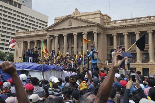 Des manifestants, dont beaucoup portent des drapeaux sri-lankais, se rassemblent devant le bureau du président à Colombo, Sri Lanka, le samedi 9 juillet 2022 