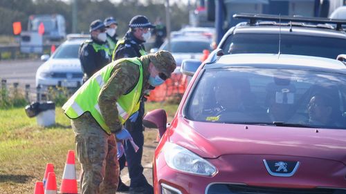 Members of the ADF and Victoria Police work together at a vehicle checkpoint.