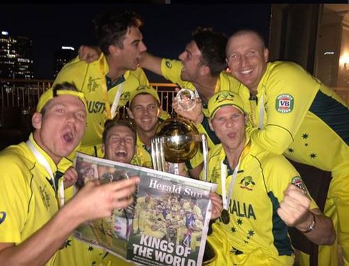 The team holds a copy of the Herald Sun featuring the World Cup win on the front cover. (Twitter @darren_lehmann)