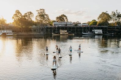 Small group enjoying stand up paddleboarding in the river, Echuca-Moama