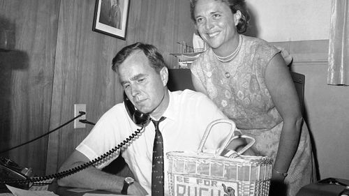 In this June 6, 1964, file photo George H.W. Bush, candidate for the Republican nomination for the US Senate, gets returns by phone at his headquarters in Houston, as his wife Barbara, smiles at the news.