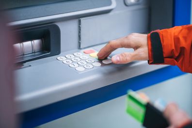 Close up as he puts bank card into machine and enters code