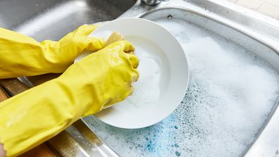 Wearing rubber gloves washing the dishes