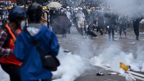 Protesters try to retreat through tear gas smoke canisters away from them during the demonstration.