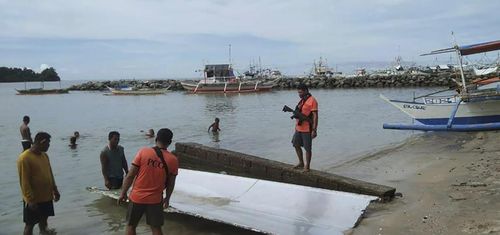 In this handout photo provided by the Philippine Coast Guard, Coast Guard personnel inspect debris, which the Philippine Space Agency said has markings of the Long March 5B (CZ-5B) Chinese rocket that was launched on July 24,