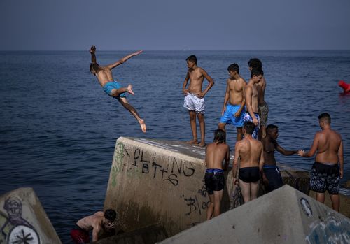 A man jumps into the sea on a breakwater in Barcelona, Spain.