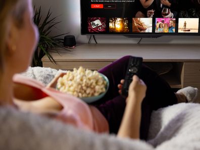 woman watching TV eating popcorn