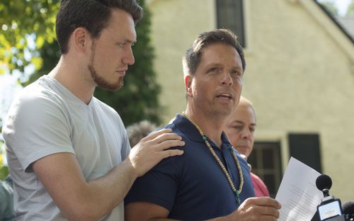 Don Damond (R), fiance of Justine Ruszczyk, makes a statement to the media as his son Zach Damond (L) comforts him