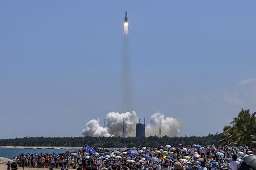 FILE - In this photo released by Xinhua News Agency, people gather at the beach as they watch the Long March 5B Y3 carrier rocket, carrying Wentian lab module, lift off from the Wenchang Space Launch Center in Wenchang in southern China's Hainan Province on July 24, 2022. 