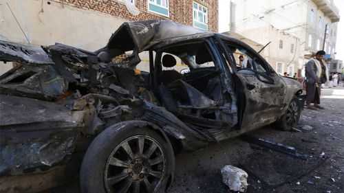 A Yemeni stands beside a car destroyed in the suicide attack. (AAP)