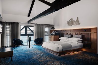 A mirrored bed base coupled with accent lighting makes the bed almost appear  to float on the water-like carpet.