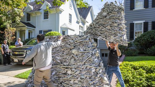 As police and Secret Service look on, a twelve-foot tall pile of artificial human bones at a vaccine equity demonstration is dismantled at the home, left, of White House Chief of Staff Ron Klain. 