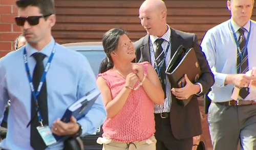 The woman smiles at the detective as she's led away. (9NEWS)