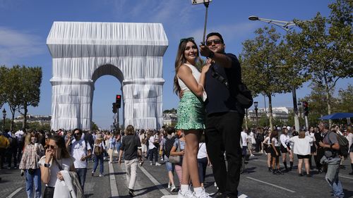 Tourists posed for a selfie in front of the wrapped Arc de Triomphe monument in Paris. 