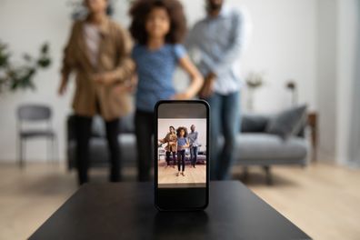 Mobile phone recording happy African American parents and kid dancing together at home for camera, shooting video post for blog, vlog. Smartphone screen close up with blurred dancers in background family vlogger